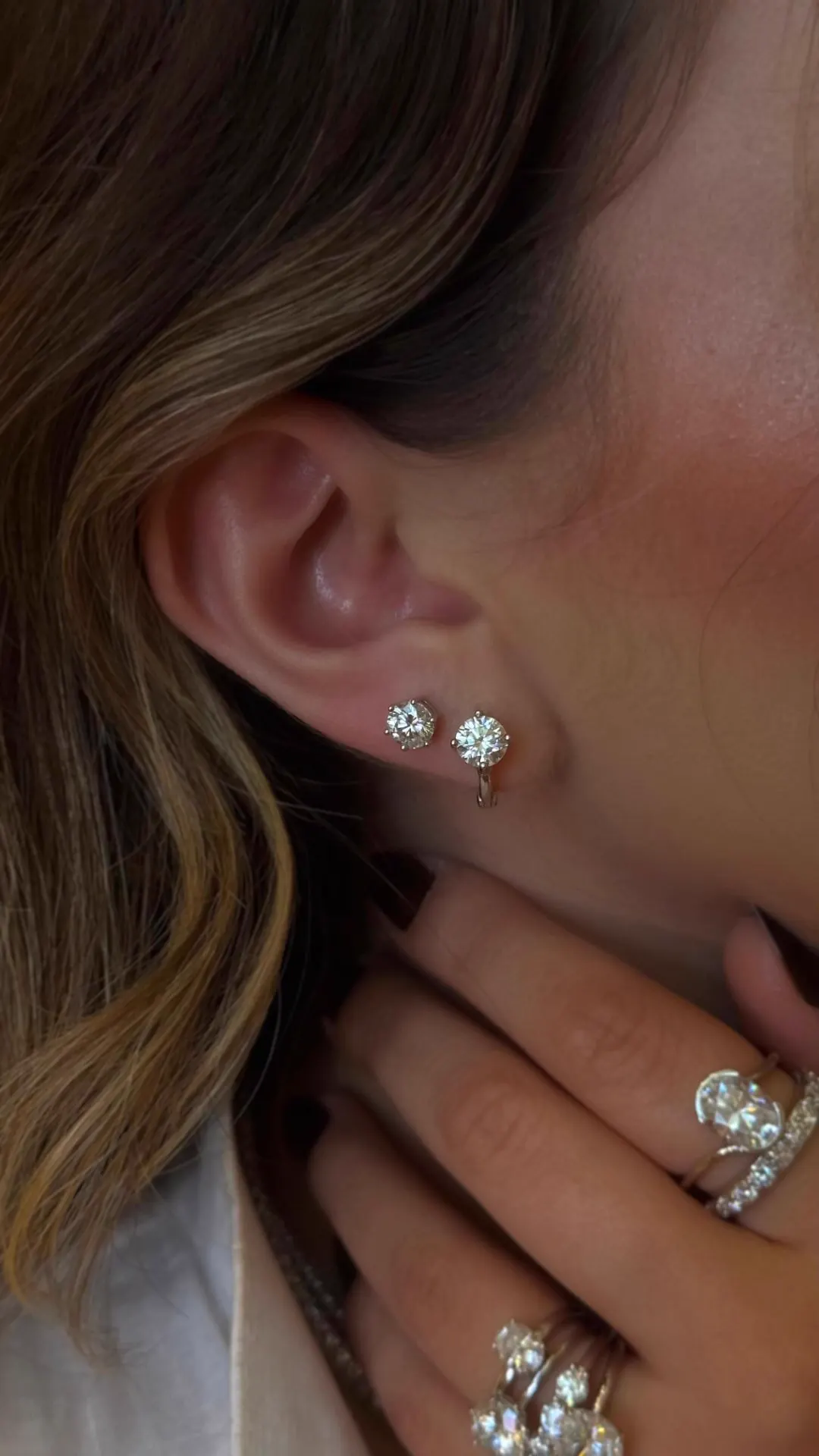 Brincos de zircônia brilhantes em orelha feminina com anéis delicados em mão, joias e semijoias Ora Joias